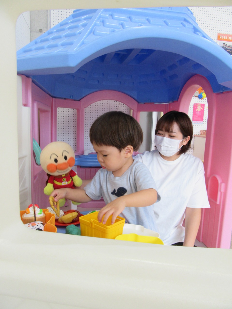 写真:アンパンマンのぬいぐるみにごちそうを作っている様子(ままごと)