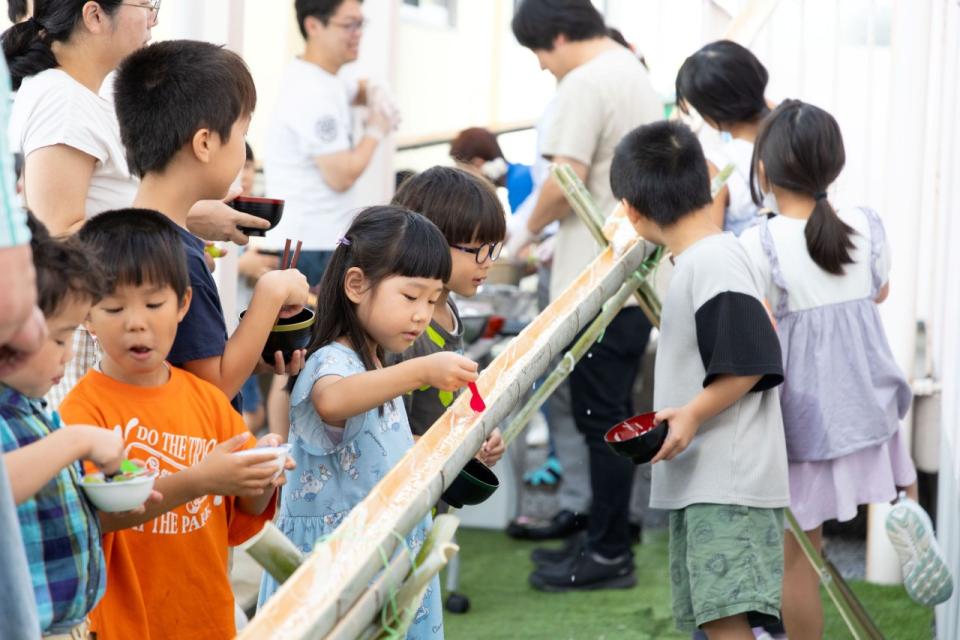 こども達が流しそうめんを楽しんでいる写真