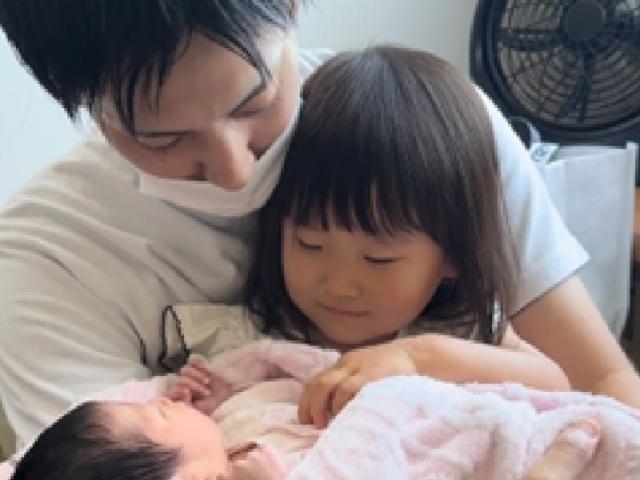 パパと女の子が赤ちゃんを見ている様子の画像